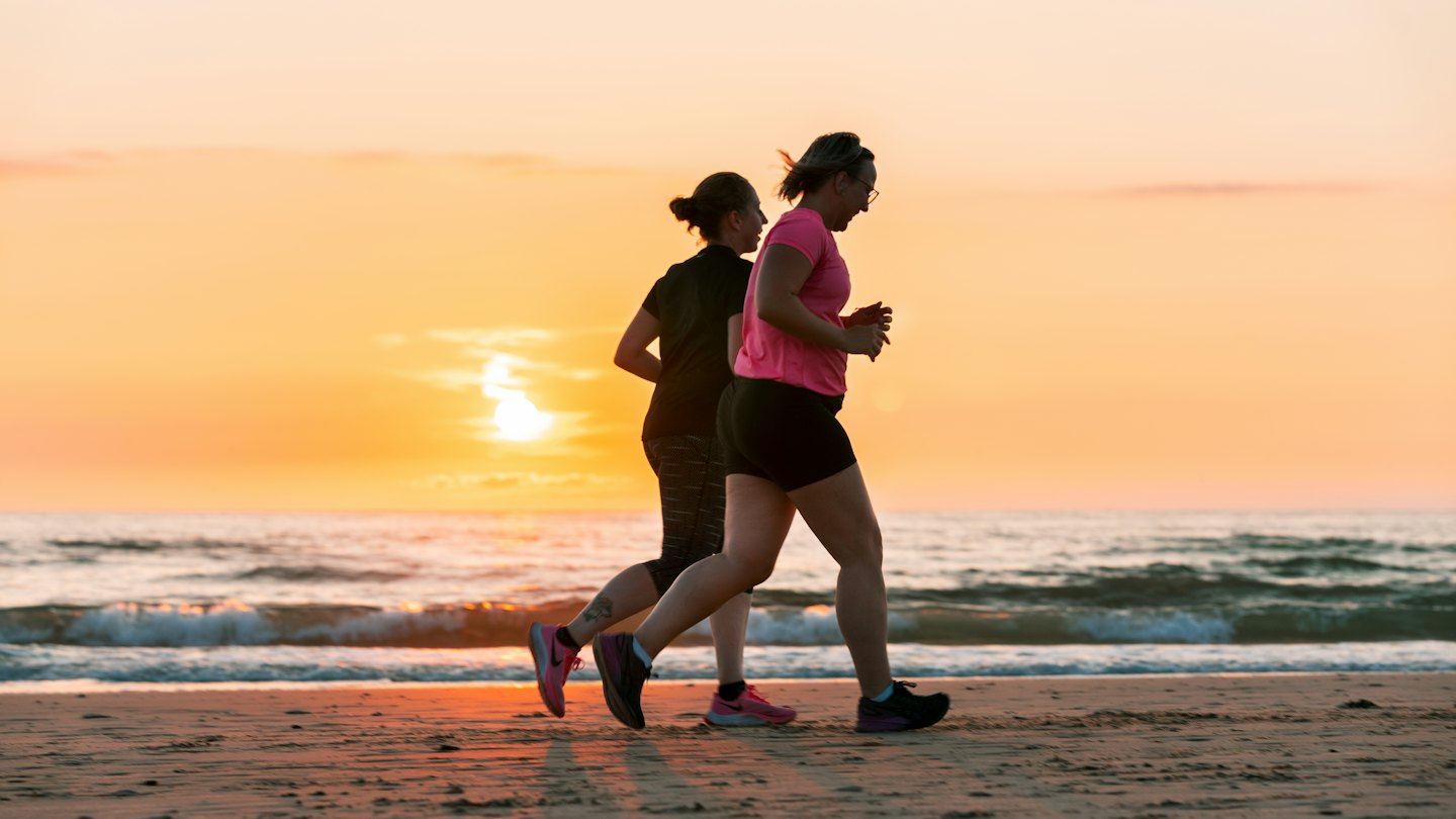 Two women over 40 running together at the beach